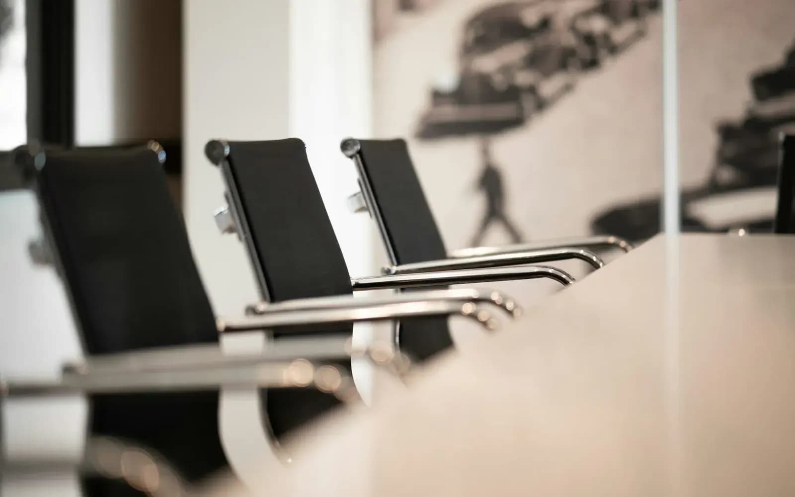 Reihe schwarzer Bürostühle an einem Konferenztisch